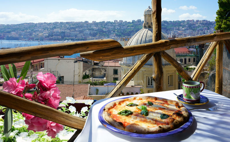 table with pizza overlooking city on visit to Naples