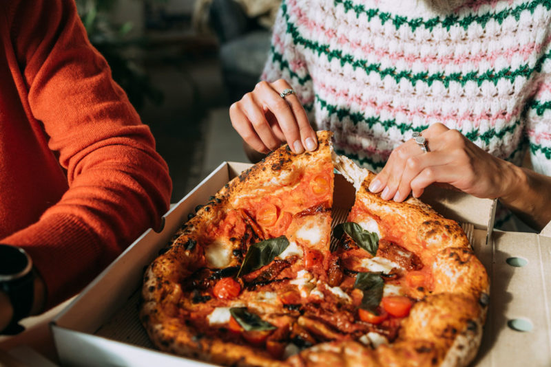 couple eating an authentic Italian handmade takeaway pizza in italy