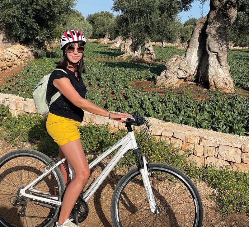 Kate Wickers cycling through olive grove in puglia
