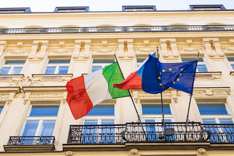 italian and european flags and other flag on a balcony - representing consulate where you can apply for italian citizenship abroad