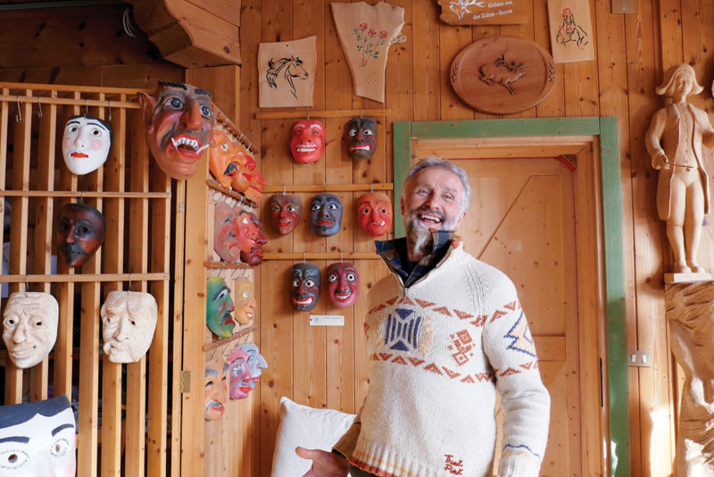 Traditional woodcrafter in Sauris Italy with carved masks on wall